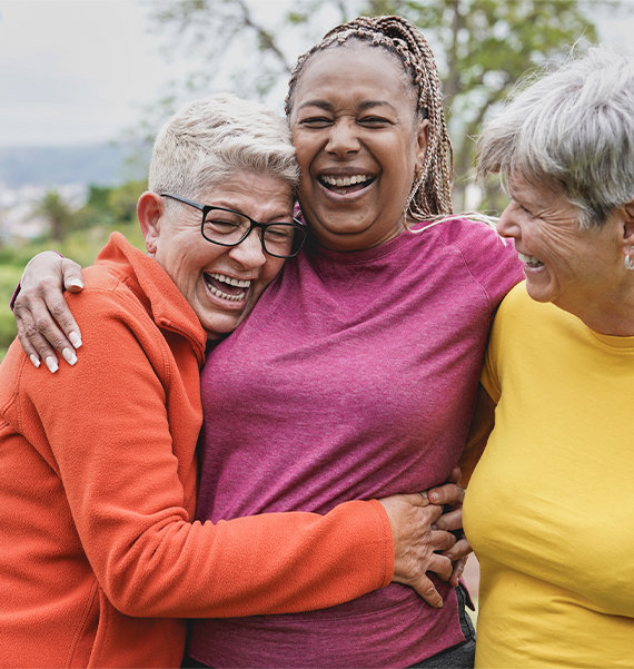 3 senior women hugging and laughing